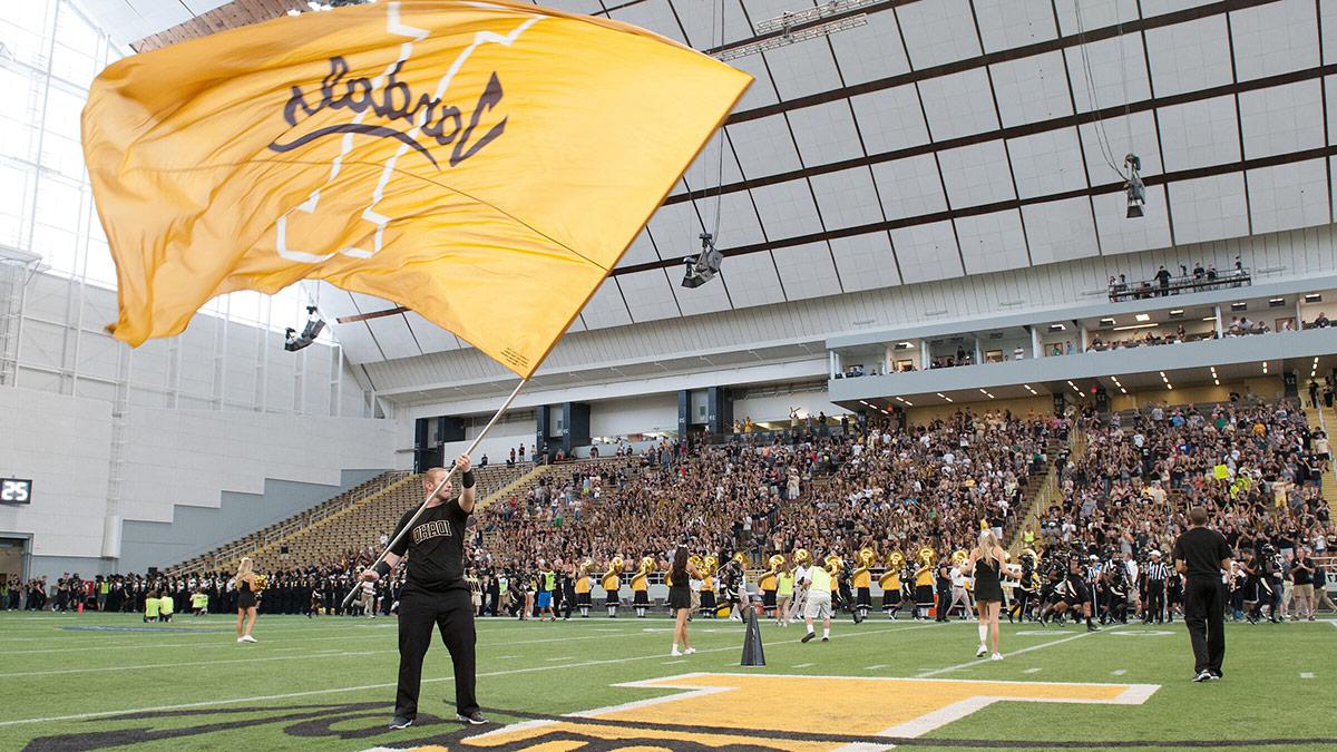 Someone waves a giant gold Idaho V和als flag on the football field in the P1FCU KIbbie Dome.