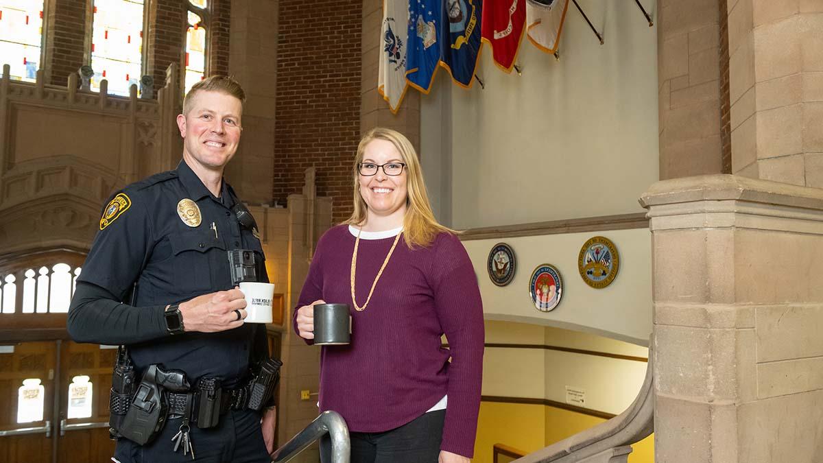 校友和运营教育奖学金获得者Jennifer Tengono和Jason House在纪念体育馆的大厅里拿着咖啡杯