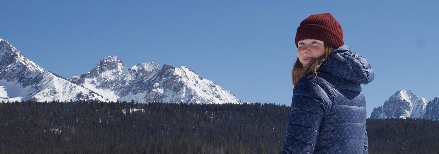 女子在滑雪山上的照片，背景是山.
