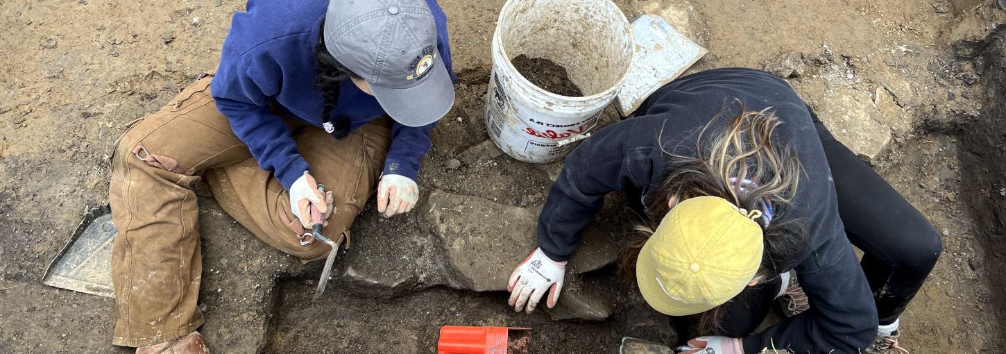 两个学生用铲子在一个长方形的坑里挖土.