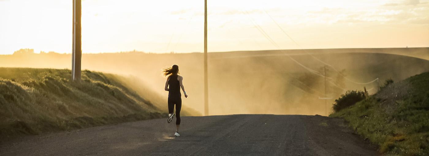 Photo of woman running down a dirt road.
